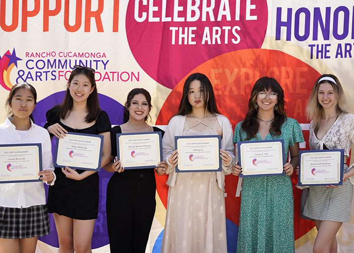 6 females standing and holding certificates in front of colorful backdrop