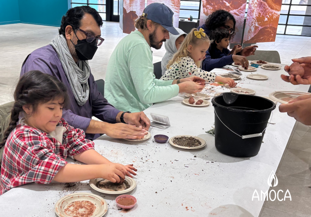 several children and adults seated at table manipulating clay with their hands