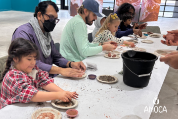 several children and adults seated at table manipulating clay with their hands